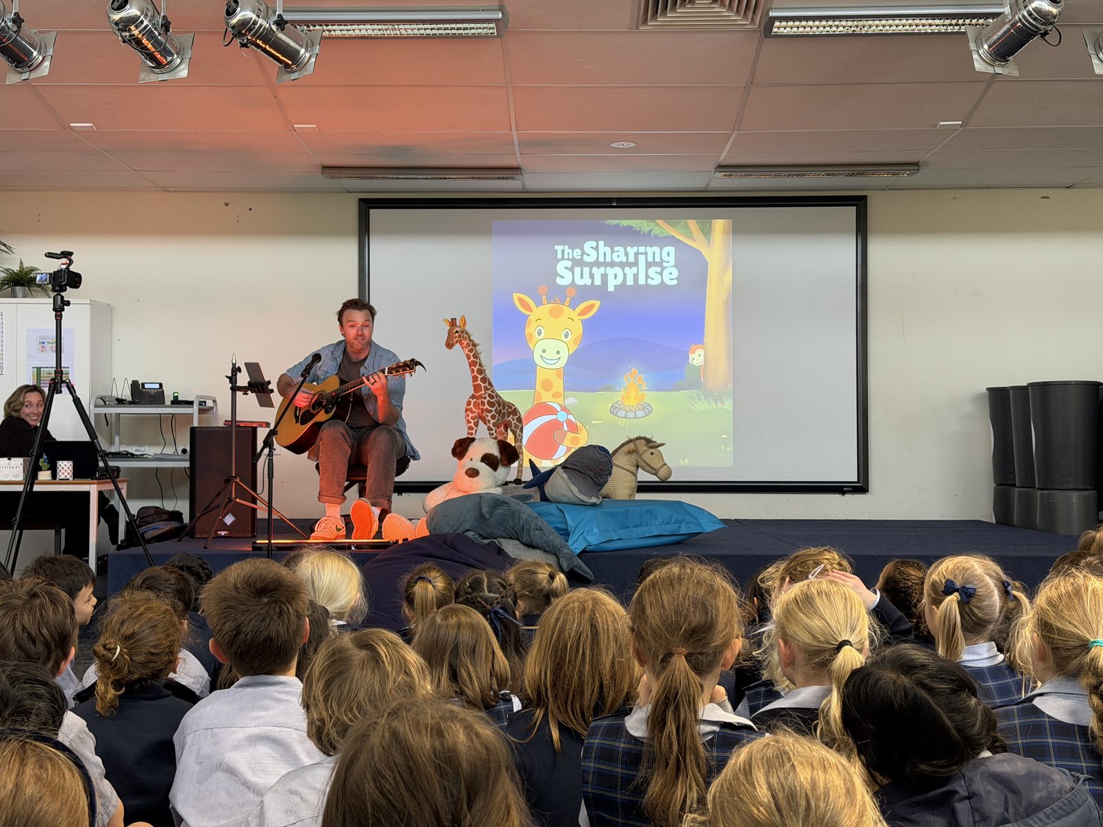 Mr H playing guitar during a One More Story school performance